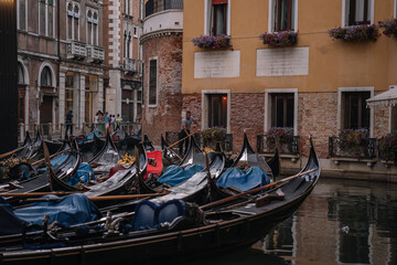 Fototapeta na wymiar Many ampty gondolas and one gondolier, and tourists walk in the background in Venice, Italy.