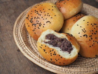 Bread bun with black sesame seed topping stuffed with sweet red bean paste in basket