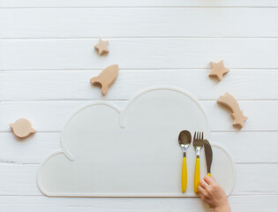 Plate on cloud napkin near wooden toys on white wooden background