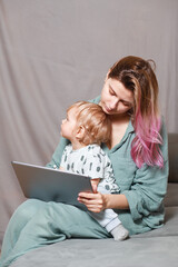 A young woman works at home with a tablet computer, along with a child.the son wants to communicate...