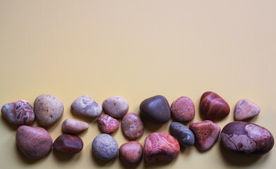 Sea smooth stones against the background of the color of yellow sand. Abstract background with space for text