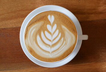 Top view hot coffee cappuccino latte art flower shape in ceramic cup on wooden table background