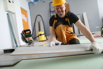 Happy carpenter places laminate panels on floor