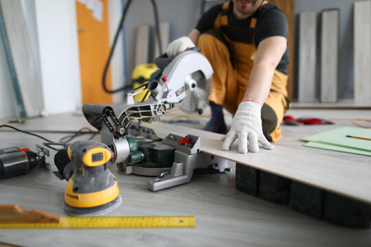 Repairman Sawing Laminate Panels Floor In Room