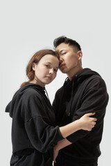 Support. Trendy fashionable couple isolated on white studio background. Stylish woman and man posing in basic minimal stylish clothes equally suitable for both. Concept of equality, inclusive.