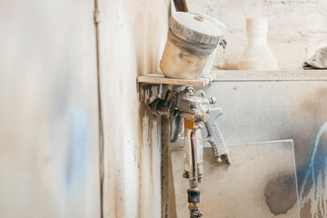 View of the paint shop of carpentry.  Three spray guns hang on the wall, close up view
