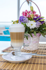 Latte in a glass with blurred background of a beautiful bouquet of flowers