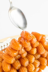 Traditional Turkish Fried Dough Dessert,Tulumba,puring syrup with spoon on the shiny metal tray.