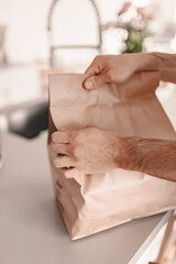 Obraz premium Unpacking paper bag food delivery from restaurant. Chinese food online order. Family dinner. No cooking. New normal. Recycle craft package. Sero waste. Quarantine life. Man pull out meal. Lunch time