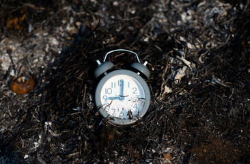 An old-fashioned clock concept resting on a fire that has gone out.