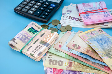 different hryvnia coins and calculator on a blue background. Much money. Financial concept.