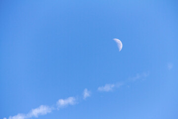 Moon out during the day with blue skies