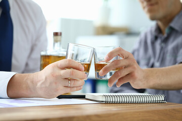 Men in suits drink alcohol in workplace at office