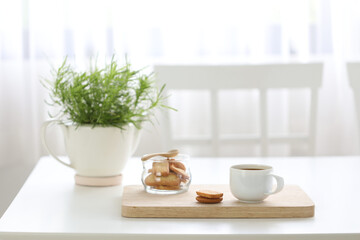 coffee with cookies on white desk with green plant pot minimal cozy home