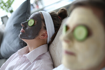 People are lying on couch with cosmetic mask faces