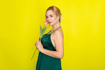 Blonde woman in green dress holding one pink tulip