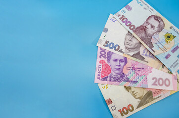 different Ukrainian hryvnias on a blue background. Hryvnia with a fan. Copy of space.