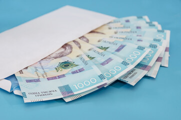 1000 hryvnia in a white envelope on a blue background. Close-up.