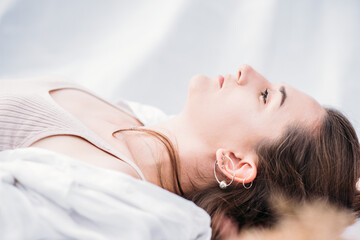 Portrait of a young woman with natural makeup. Dressed in a white shirt. The woman lies on a white background. side view
