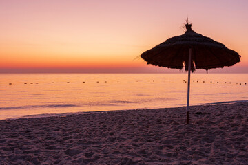 Sunrise on the beach with parasol overlooking the sea