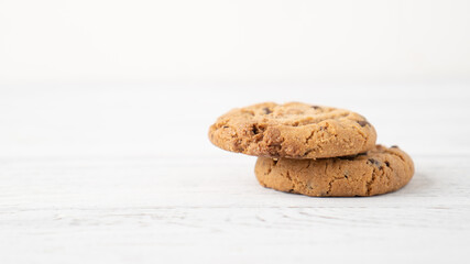 Two cookies with chocolate drops on white wooden table. Chocolate chip cookie. Morning portion of cookies. Text space