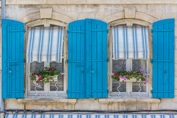 Flowerboxes are the centerpiece for bright blue shutters and striped awnings in Provence, France