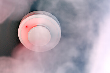 Dire alarm smoke detector with red LED indicator on ceiling
