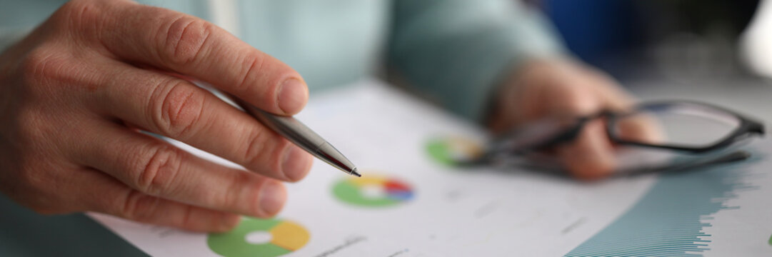 Male hand holding paper with financial statistics