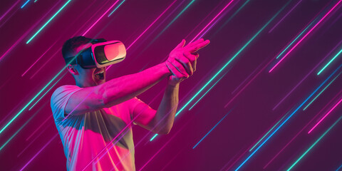 Man playing with VR-headset. Creative portrait with copyspace. Neon lighted, colored portrait with neon lines, flyer, proposal. Motion, action, youth culture concept. Contemporary art, modern design.