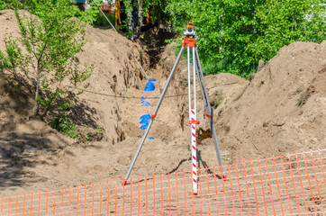 The trench with a plastic pipe and a theodolite