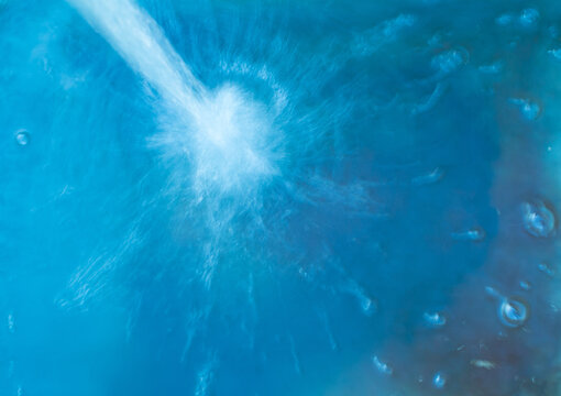 A stream of water flows under a great pressure into the container blue color © IURII