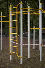 Fototapeta premium Empty outdoor fitness equipment wrapped with warning red and white tape during quarantine period of COVID-19