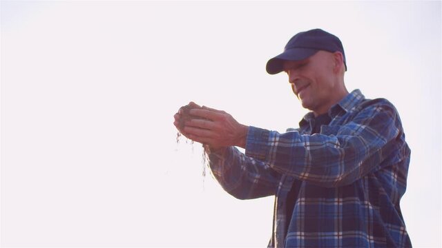 Farmer Examining Soild Dirt in Hands at Dusk