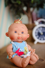 Cute doll sits on the wood background.