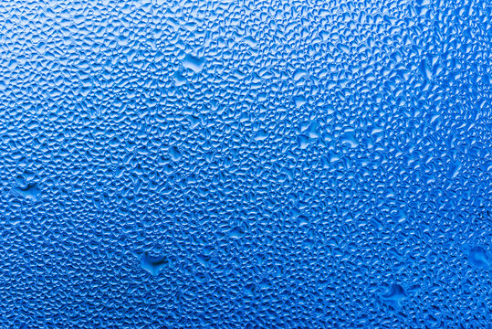 Macro photography of water drops on glass window blue background after the rain