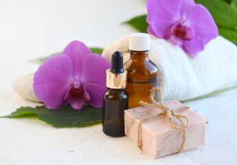 Fototapeta na wymiar Spa aromatherapy bathe still life composition. Essential oil bottle, dropper, soap bar and orchid over light background. Organic cosmetic or herbal medicine concept. Tropical relax. Wellness