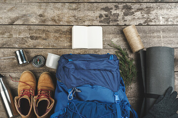 Backpack and hiking equipment on wooden background, top view