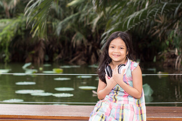 pretty little girl listen to music with earphone in garden to relax