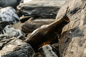 Empty glass beer bottle on rocky sea shore,polluted coast in cilento,italy