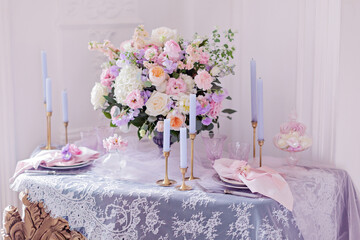 Wedding table decor. Beautiful bouquet with roses and peonies. Lace tablecloth and candles in candlesticks