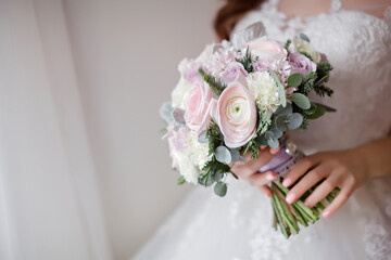 The bride holds a beautiful bouquet of roses and peonies