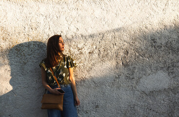Fototapeta premium Beautiful young woman relaxing and enjoying sun at sunset. Rustic white background