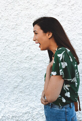 Emotional brunette woman opening her mouth and with her hands on her chest widely screaming loudly being dissatisfied with something expressing disagreement and annoyance.