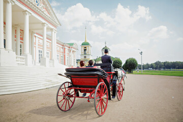 The bride and groom ride in a carriage with a horse at the Palace