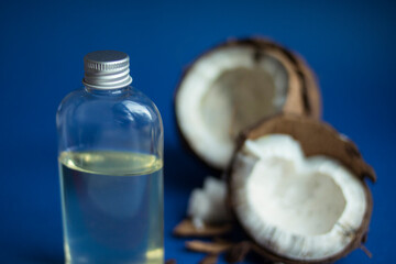 Beautiful open coconut with  liquid transparent melted coconut oil on a blue background