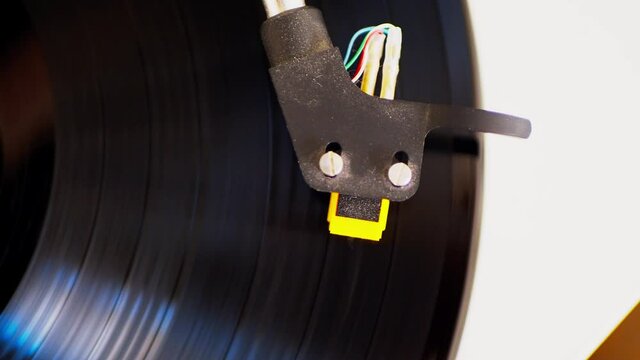 Looking down at the head cartage of a turntable with a record spinning 