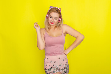 Blonde woman in summer clothing wearing pink headphones