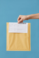 Close-up of postman holding registered letter against the blue background