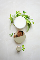 cosmetic jar with face cream with sage leaves and green branches on a light background. The concept of natural ingredients in cosmetics 