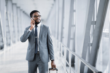 African Entrepreneur Having Phone Conversation Walking With Suitcase Through Airport